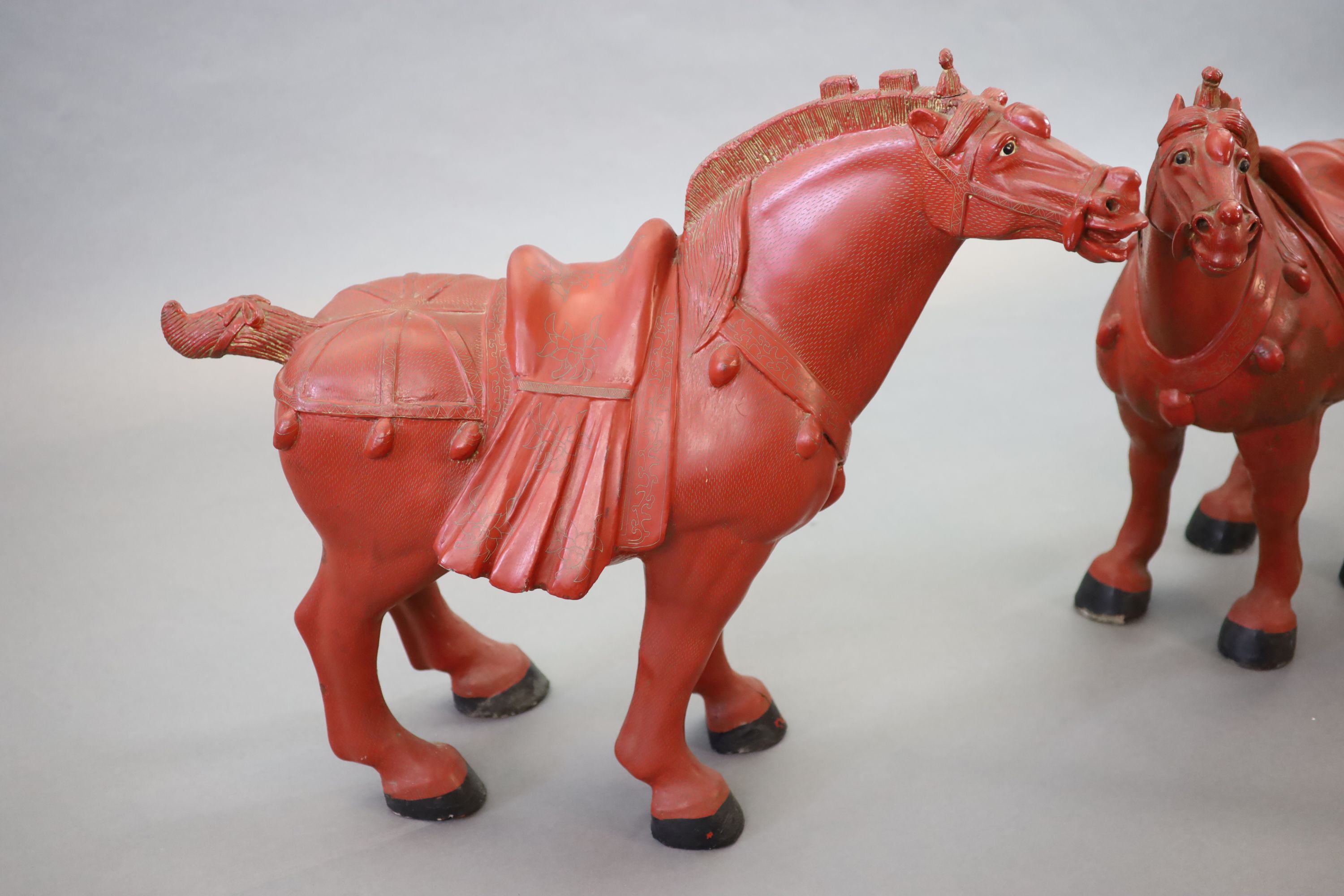 A pair of Chinese cinnabar lacquered horses with plinth stands